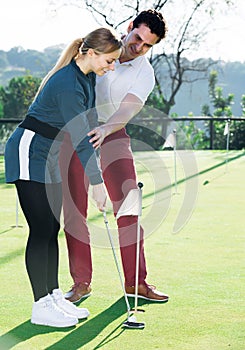 Golf player explaining to woman to play golf