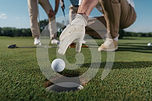 Golf player in glove trying to get ball near the hole