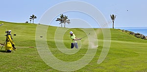 Golf player hits the ball from the bunker