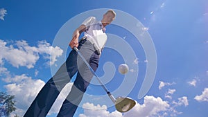 Golf player juggles a ball, using golf club.