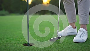 Golf player legs relax at golfing ball hole. Golfer posing on green lush course.