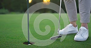 Golf player legs relax at golfing ball hole. Golfer posing on green lush course.