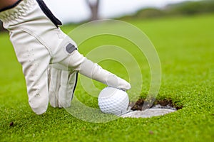 Golf player man pushing golfball into the hole