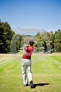 Golf player performs a tee shot photo