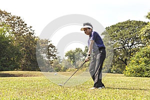 Golf player pitching golf ball in the air.