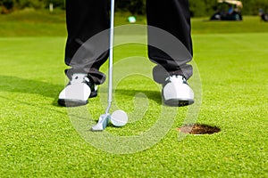 Golf player putting ball in hole