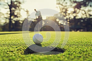 golf player putting golf ball into hole