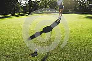 golf player putting golf ball into hole