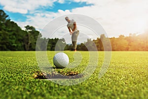 golf player putting golf ball into hole