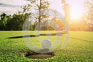 golf player putting golf ball into hole