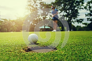 golf player putting golf ball into hole