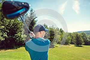 Golf player at the tee on golf course swinging the driver