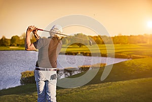 Golf player teeing-off at sunset.