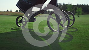 Golf player using clubs trolley on course. Golfer legs walk take sport equipment