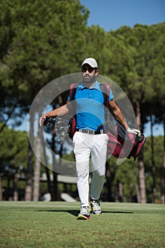 Golf player walking and carrying bag