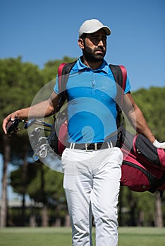 Golf player walking and carrying bag