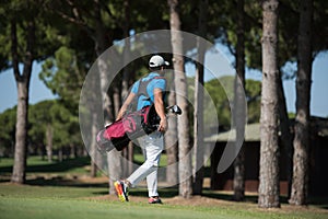 Golf player walking and carrying bag