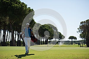 Golf player walking and carrying bag