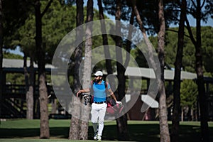 Golf player walking and carrying bag