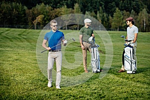 Golf player walking and carrying bag on course during summer gam