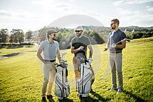 Golf player walking and carrying bag on course during summer gam