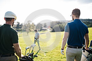 Golf player walking and carrying bag on course during summer gam