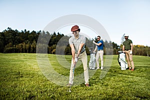 Golf player walking and carrying bag on course during summer gam