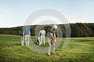 Golf player walking and carrying bag on course during summer gam