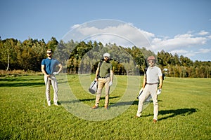 Golf player walking and carrying bag on course during summer gam