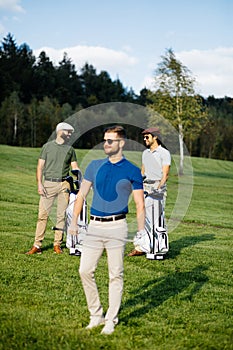 Golf player walking and carrying bag on course during summer gam