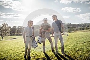 Golf player walking and carrying bag on course during summer gam