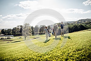 Golf player walking and carrying bag on course during summer gam