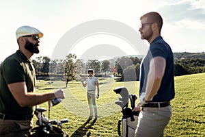 Golf player walking and carrying bag on course during summer gam