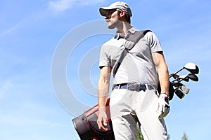 Golf player walking and carrying bag on course during summer game golfing