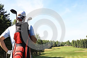 Golf player walking and carrying bag on course during summer game golfing