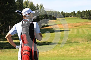 Golf player walking and carrying bag on course during summer game golfing