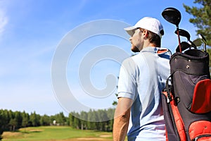 Golf player walking and carrying bag on course during summer game golfing