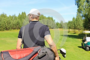 Golf player walking and carrying bag on course during summer game golfing