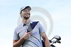 Golf player walking and carrying bag on course during summer game golfing