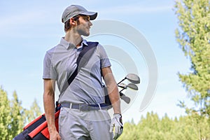 Golf player walking and carrying bag on course during summer game golfing