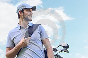 Golf player walking and carrying bag on course during summer game golfing