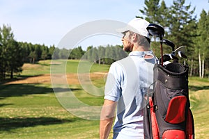 Golf player walking and carrying bag on course during summer game golfing