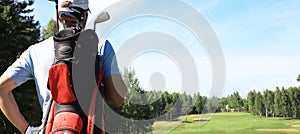 Golf player walking and carrying bag on course during summer game golfing