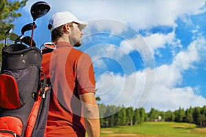 Golf player walking and carrying bag on course during summer game golfing.