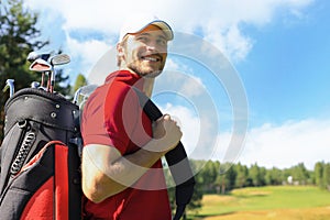 Golf player walking and carrying bag on course during summer game golfing.