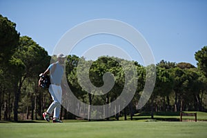 Golf player walking and carrying bag