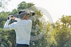 Golf Player in white shirt swinging glof. Young man practicing his swing on the golf course