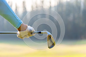 Golf player woman holding a golf club in golf course.