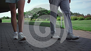 Golf players legs walking grass country club course on sunny summer morning.