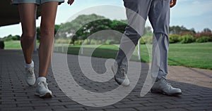 Golf players legs walking grass country club course on sunny summer morning.